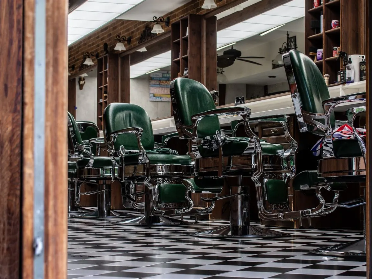 Salão da barbearia com cadeiras clássicas e piso quadriculado
